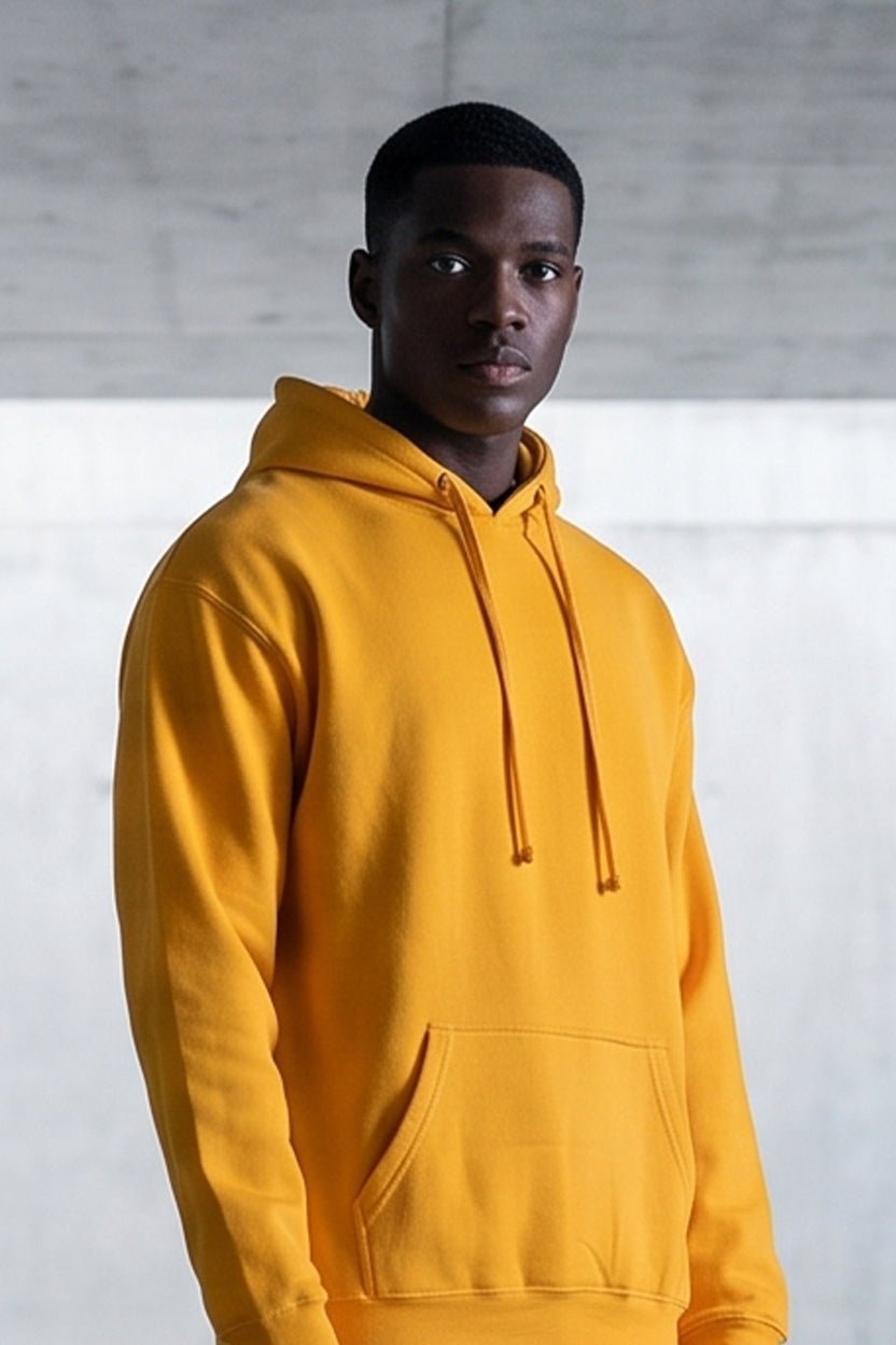 Man wearing a gold wholesale fleece pullover hoodie from S&S Textile and Apparel Inc., standing in a concrete architectural space, mobile view